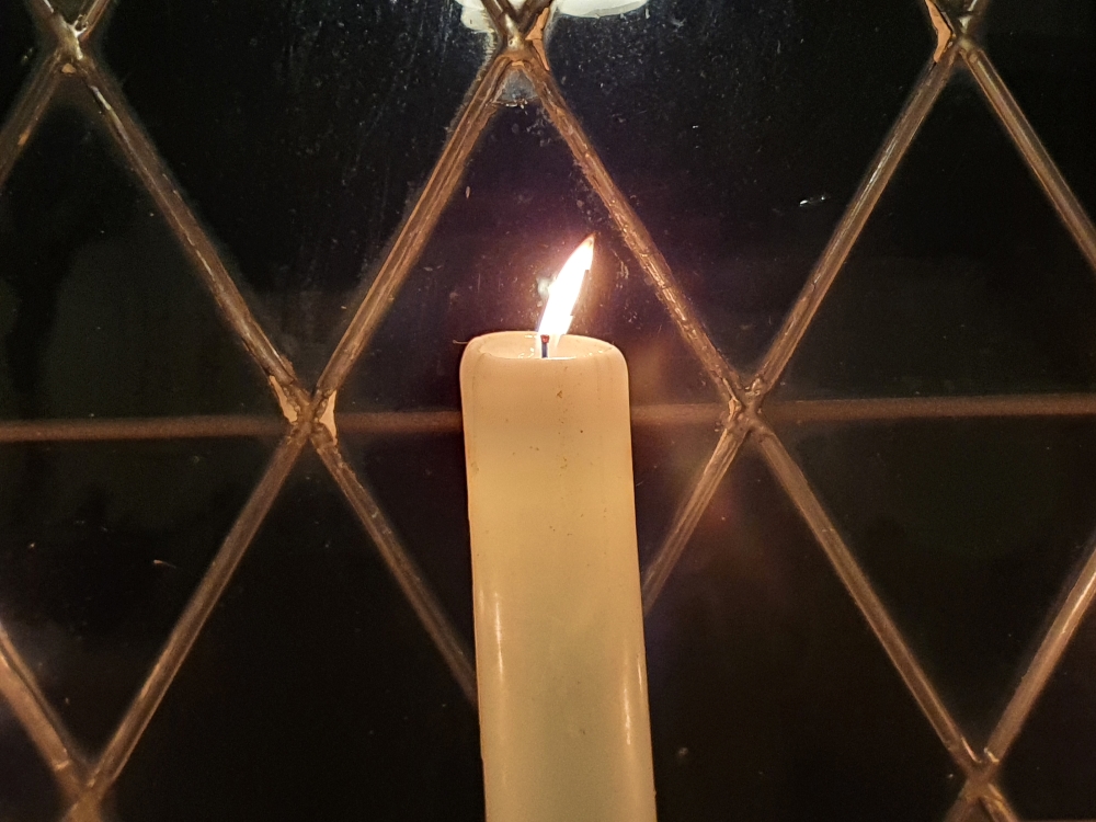 brennende Kerze im Fenster